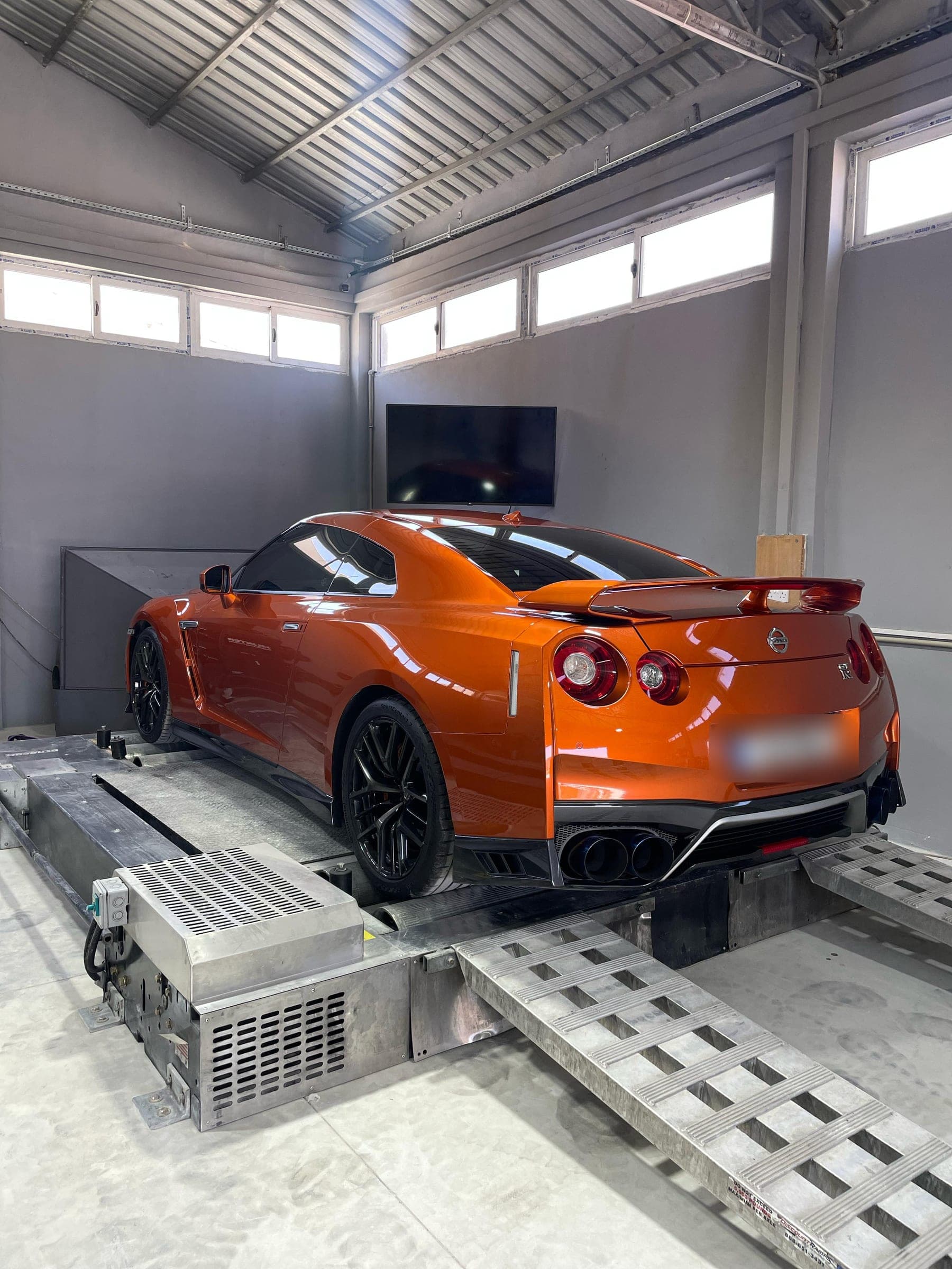 Şasi dinamometresinin makaraları üzerinde turuncu bir Nissan GT-R