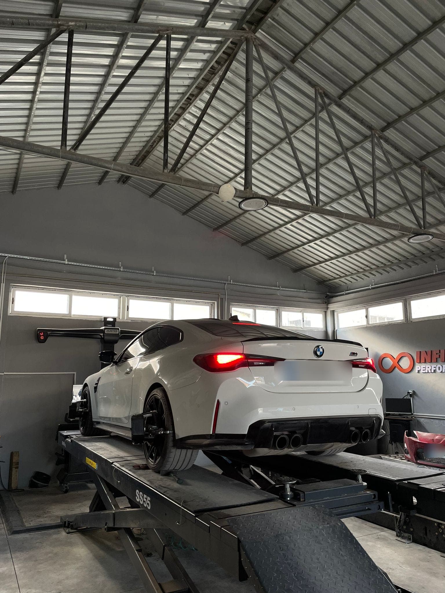 Makaslı liftte, tekerleğine rot ayar hedefi takılmış beyaz bir BMW