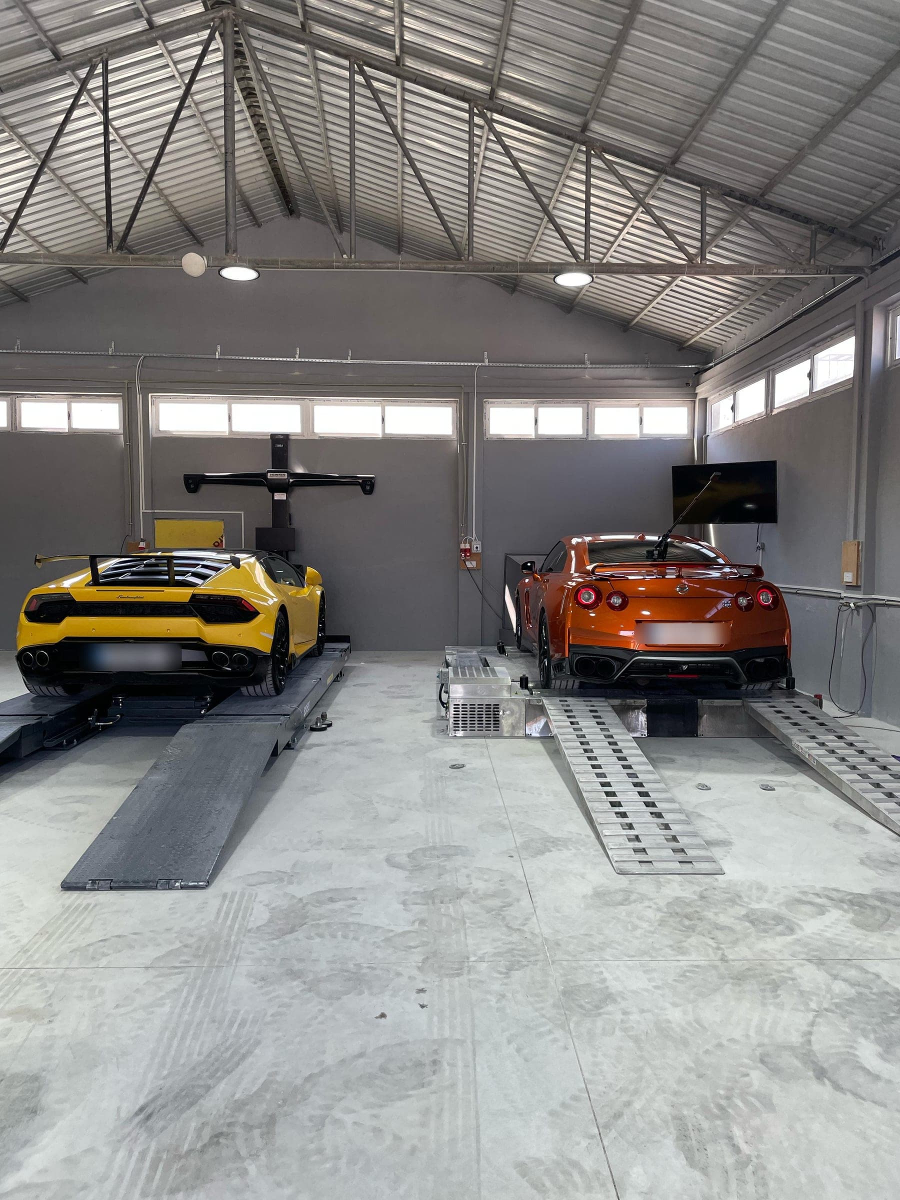 Rot ayarı liftinde sarı bir Lamborghini, dinamometrede turuncu bir Nissan GT-R